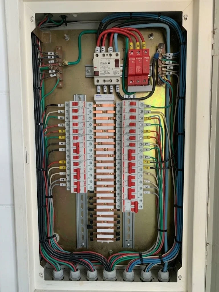 Quadro elétrico com disjuntores, fiação e DPS na parte superior.